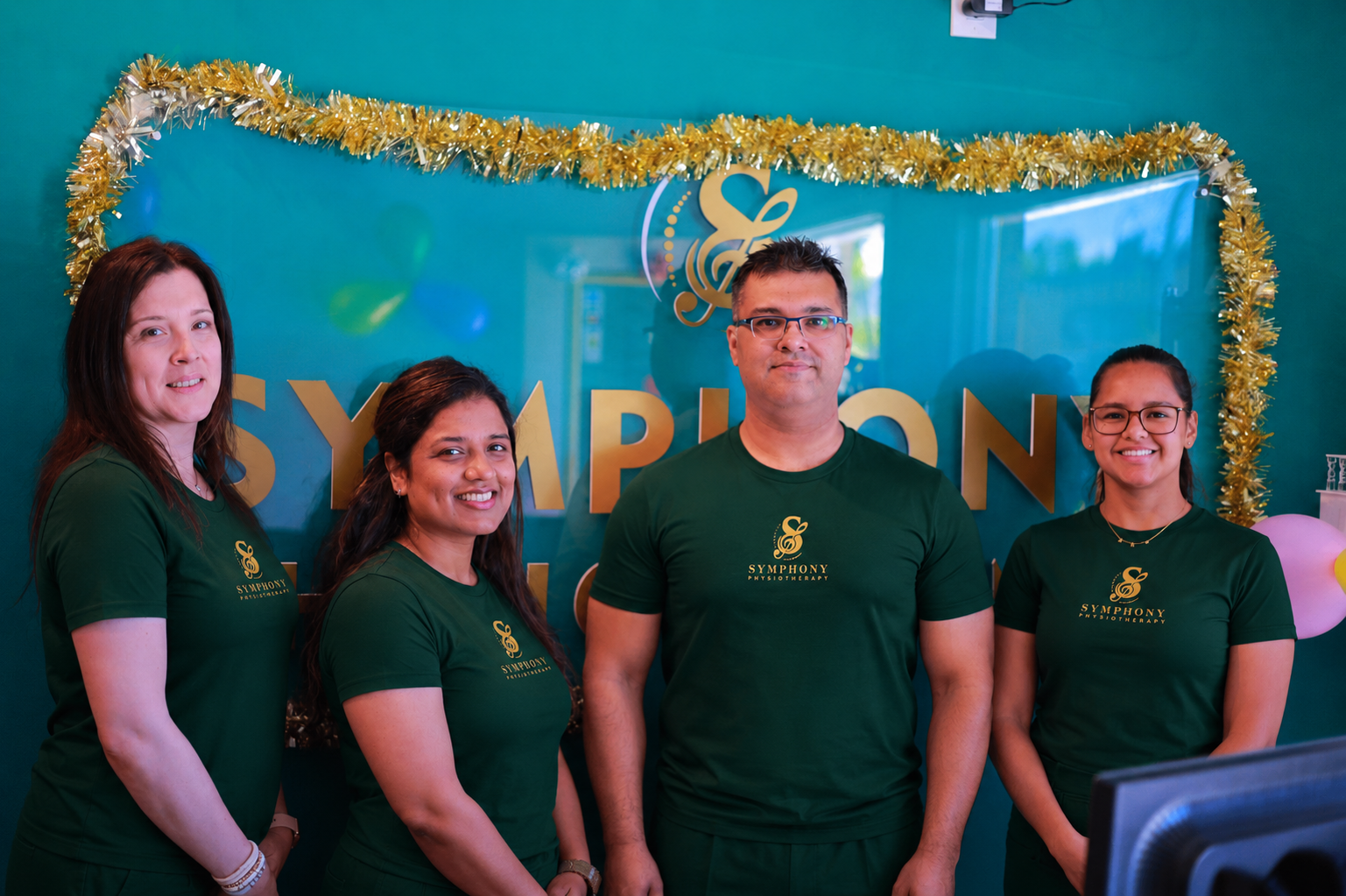 Symphony Physiotherapy team standing in front of the clinic reception sign